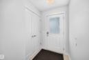 Entryway featuring a white paneled door with frosted glass insert, contrasting dark floor mat, and adjacent double-door closet with satin nickel hardware - 2433 Glenridding Boulevard, Edmonton, AB 