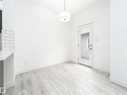 Bright dining area featuring light wood-finish flooring, a contemporary drum pendant light fixture, and a full-light exterior door - 