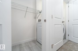 Utility area featuring tile flooring, white walls, and a wire shelving system - 