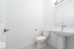 Pedestal sink with chrome faucet, wall-mounted mirror, and vanity lighting - 