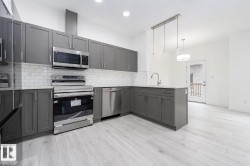 Modern kitchen featuring stainless steel appliances, grey cabinetry, white subway tile backsplash, and light wood-finish flooring - 