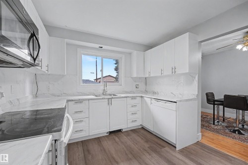 Modern kitchen featuring white cabinetry, stone-finish countertops, and matching backsplash - 12707 87 Street, Edmonton, AB 