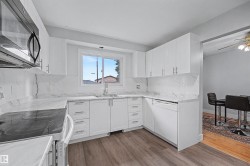 Modern kitchen featuring white cabinetry, stone-finish countertops, and matching backsplash - 
