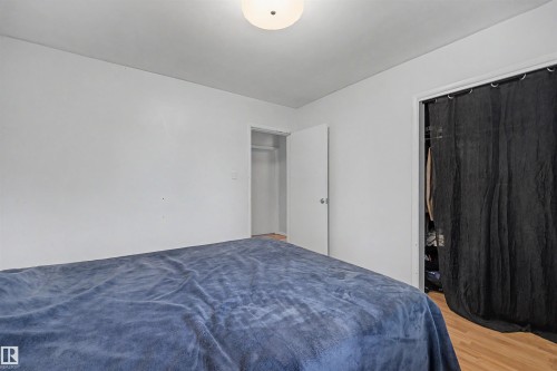 Bedroom featuring neutral white walls, wood-finish flooring, and a ceiling-mounted light fixture - 12707 87 Street, Edmonton, AB 