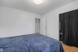 Bedroom featuring neutral white walls, wood-finish flooring, and a ceiling-mounted light fixture - 