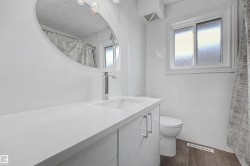 Modern bathroom featuring a white vanity with an integrated sink, chrome faucet, and oval mirror - 
