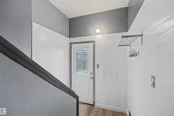 Entryway featuring a white door with decorative glass inserts, wood-finish flooring, and white horizontal paneling - 