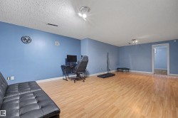 Spacious room featuring wood-finish flooring, light blue walls, and white baseboards - 