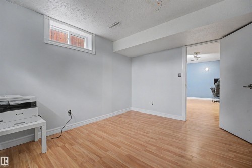 Room featuring wood-finish flooring, light gray walls, and a white trim baseboard - 12707 87 Street, Edmonton, AB 