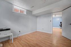 Room featuring wood-finish flooring, light gray walls, and a white trim baseboard - 