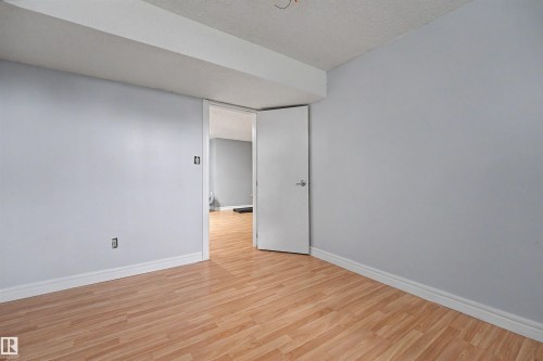 Room featuring light wood-finish flooring, light grey painted walls, and white baseboards - 12707 87 Street, Edmonton, AB 