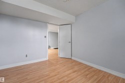 Room featuring light wood-finish flooring, light grey painted walls, and white baseboards - 