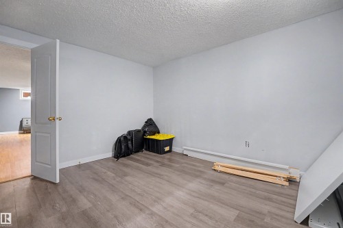 Interior room featuring light gray walls, wood-finish flooring, a white door with a brass-finish doorknob, and white baseboards - 12707 87 Street, Edmonton, AB 