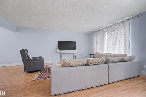 Bright living area with wood-finish flooring, light blue walls, and white baseboards - 12707 87 Street, Edmonton, AB 