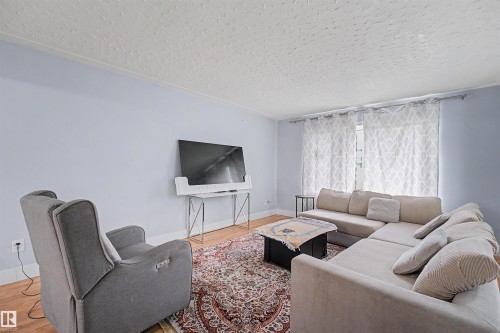 Living area featuring light wood-finish flooring and a patterned area rug - 12707 87 Street, Edmonton, AB 