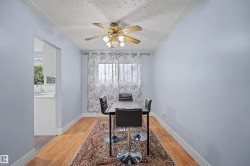 Dining area featuring wood-finish flooring, a ceiling fan with integrated lighting, and a window with sheer curtains - 