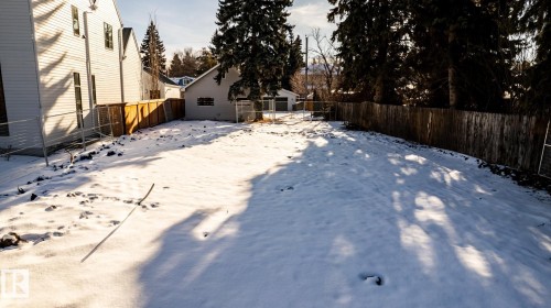 Expansive lot featuring a wooden privacy fence, mature evergreen trees, and a detached structure - 14307 Summit Drive, Edmonton, AB 