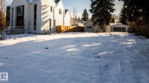 Expansive lot featuring a modern white-sided residence with tall black-framed windows, a dark roof, and an attached garage structure - 14307 Summit Drive, Edmonton, AB 