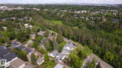 Expansive neighborhood featuring mature trees, residential properties, and a winding road - 