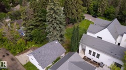 Contemporary white exterior with multiple gabled metal roofs, dark-framed windows, and an exposed basement level - 