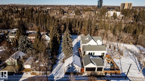 Modern white residence featuring a two-car garage with black doors, a gray standing seam metal roof, and dark window frames - 14307 Summit Drive, Edmonton, AB 