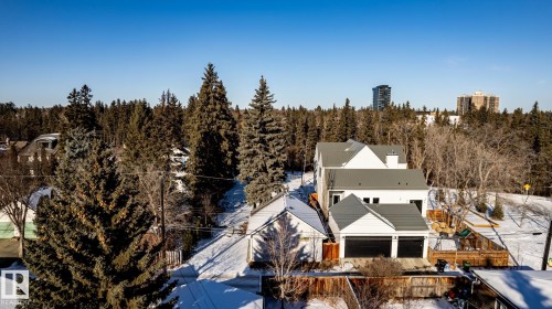 Contemporary residence featuring a white exterior, dark gray metal roof, and an attached two-car garage with black doors - 14307 Summit Drive, Edmonton, AB 