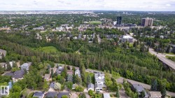 Aerial perspective showcasing a verdant urban landscape with dense tree coverage, residential properties, and distant city structures - 