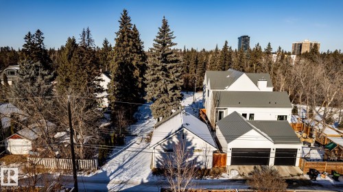 Modern white dwelling with a dark metal roof, featuring multiple gables and an attached two-car garage with dark doors - 14307 Summit Drive, Edmonton, AB 