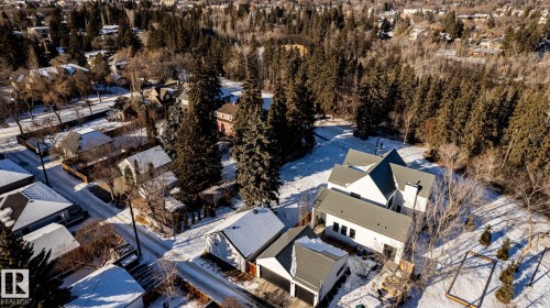 Contemporary residence with multiple gabled roofs and a striking white exterior, set against a backdrop of mature trees - 14307 Summit Drive, Edmonton, AB 