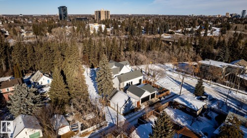 Aerial perspective showcasing a residential area bordered by dense evergreen tree coverage and distant urban architecture - 14307 Summit Drive, Edmonton, AB 