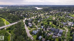 Expansive aerial landscape showcasing a river, mature tree canopy, residential properties, and distant city skyline - 