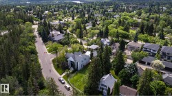 Aerial perspective showcasing a residential area surrounded by abundant mature trees and extensive green spaces - 