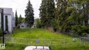Expansive grassy lot featuring mature perimeter trees, partial wood fencing, and a temporary chain-link fence - 14307 Summit Drive Nw, Edmonton, AB 