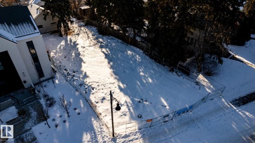 Cleared lot featuring perimeter fencing, a street lamp, and mature trees bordering the property - 14307 Summit Drive, Edmonton, AB 