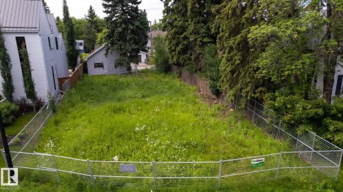 Expansive lot featuring mature perimeter trees, a chain-link fence, and a level grassy expanse - 14307 Summit Drive Nw, Edmonton, AB 