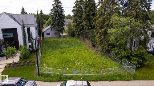 Expansive cleared lot featuring mature trees along the perimeter and a chain-link fence - 14307 Summit Drive Nw, Edmonton, AB 