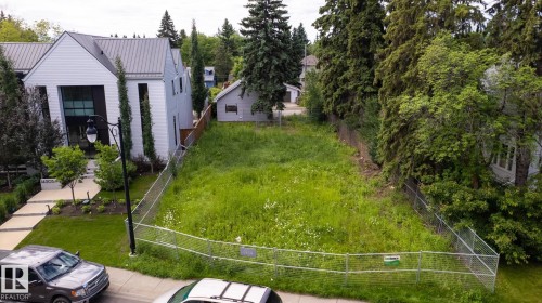 Expansive lot featuring a chain-link fence, mature trees, and existing utility infrastructure - 14307 Summit Drive Nw, Edmonton, AB 