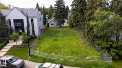 Expansive lot featuring a chain-link fence, mature trees, and existing utility infrastructure - 