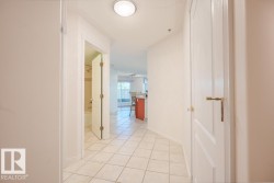 Hallway featuring square floor tiles, white baseboards, and bright overhead lighting - 