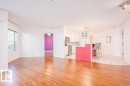 Open concept living area featuring wood-finish flooring, white walls, and a window providing natural light - 108 12028 103 Avenue, Edmonton, AB 