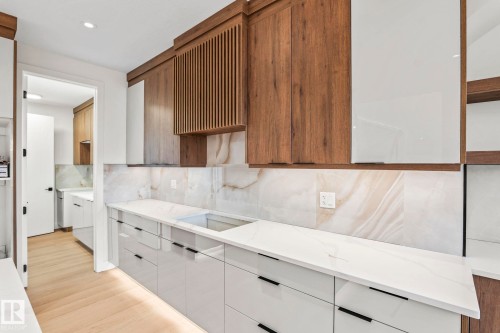 White and wood-finish cabinetry with integrated lighting, white countertops, and a stone-look backsplash - 13111 187 Avenue Nw, Edmonton, AB - Indoor Photo Showing Kitchen