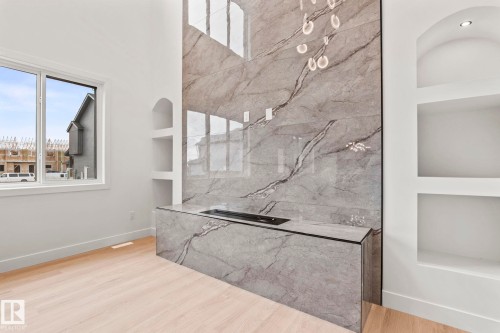 Full-height stone-finish accent wall with an integrated linear fireplace, built-in shelving, and light wood-finish flooring - 13111 187 Avenue Nw, Edmonton, AB - Indoor