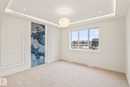 Accent wall with blue and gray abstract design, recessed ceiling lighting, decorative wall molding, window with white trim, and light-colored carpeting - 13111 187 Avenue Nw, Edmonton, AB - Indoor Photo Showing Other Room