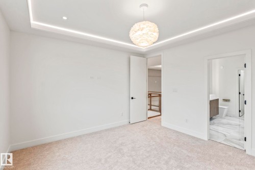 Recessed lighting, layered ceiling design, contemporary light fixture, carpeted flooring, and an adjacent bathroom with a floating vanity - 13111 187 Avenue Nw, Edmonton, AB - Indoor Photo Showing Other Room