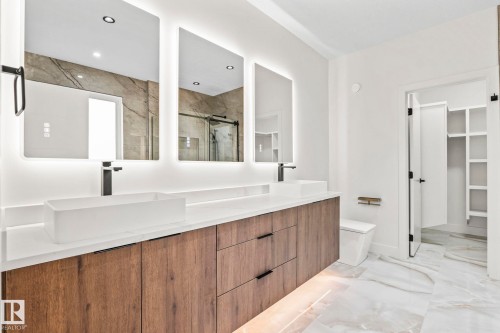 Dual vanity with matte black fixtures, back-lit mirrors, wood-finish cabinetry, and a walk-in closet with built-in shelving - 13111 187 Avenue Nw, Edmonton, AB - Indoor Photo Showing Other Room