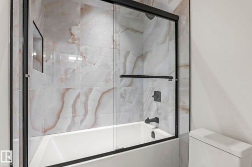 Bathtub with matte black fixtures, full-height tile surround, and a glass shower enclosure with a black frame - 13111 187 Avenue Nw, Edmonton, AB - Indoor Photo Showing Bathroom