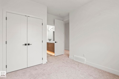 Neutral tone-on-tone carpeting, crisp white walls, and contemporary white closet doors with matte black hardware - 13111 187 Avenue Nw, Edmonton, AB - Indoor Photo Showing Other Room