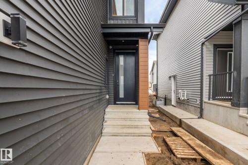 Dark gray horizontal siding, black entry door with frosted glass, concrete steps, and a contemporary exterior sconce - 13111 187 Avenue Nw, Edmonton, AB - Outdoor