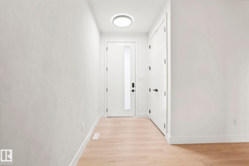Bright hallway with warm wood-finish flooring, white painted walls, recessed ceiling lighting, and multiple white interior doors with brushed nickel hardware - 13111 187 Avenue Nw, Edmonton, AB - Indoor Photo Showing Other Room