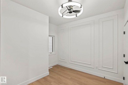 Wood-finish flooring, accent wall with decorative trim, window with blinds, and a contemporary ceiling light fixture - 13111 187 Avenue Nw, Edmonton, AB - Indoor Photo Showing Other Room